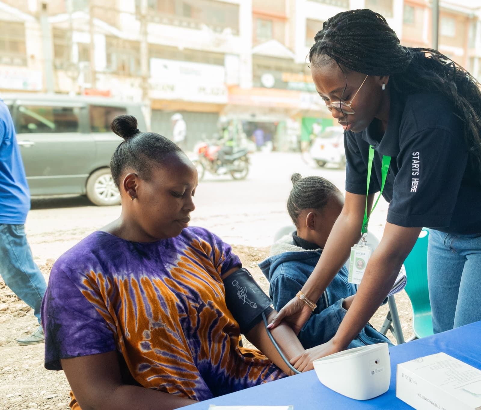 An Axcess health worker taking a patient's blood pressure at a community table